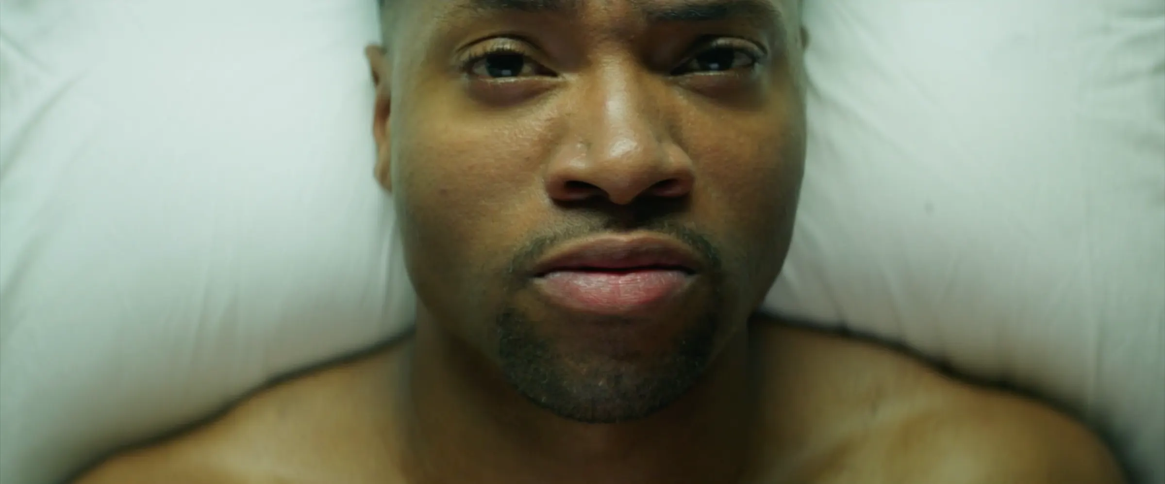 A man lies on a hospital pillow, staring upward.