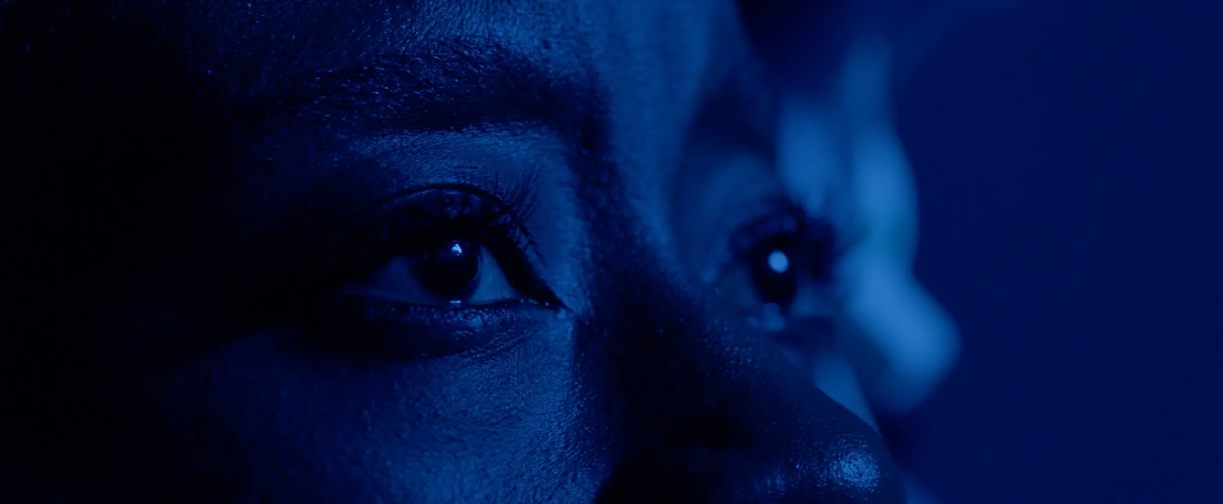 Extreme close-up of the astronaut’s eyes in blue light.
