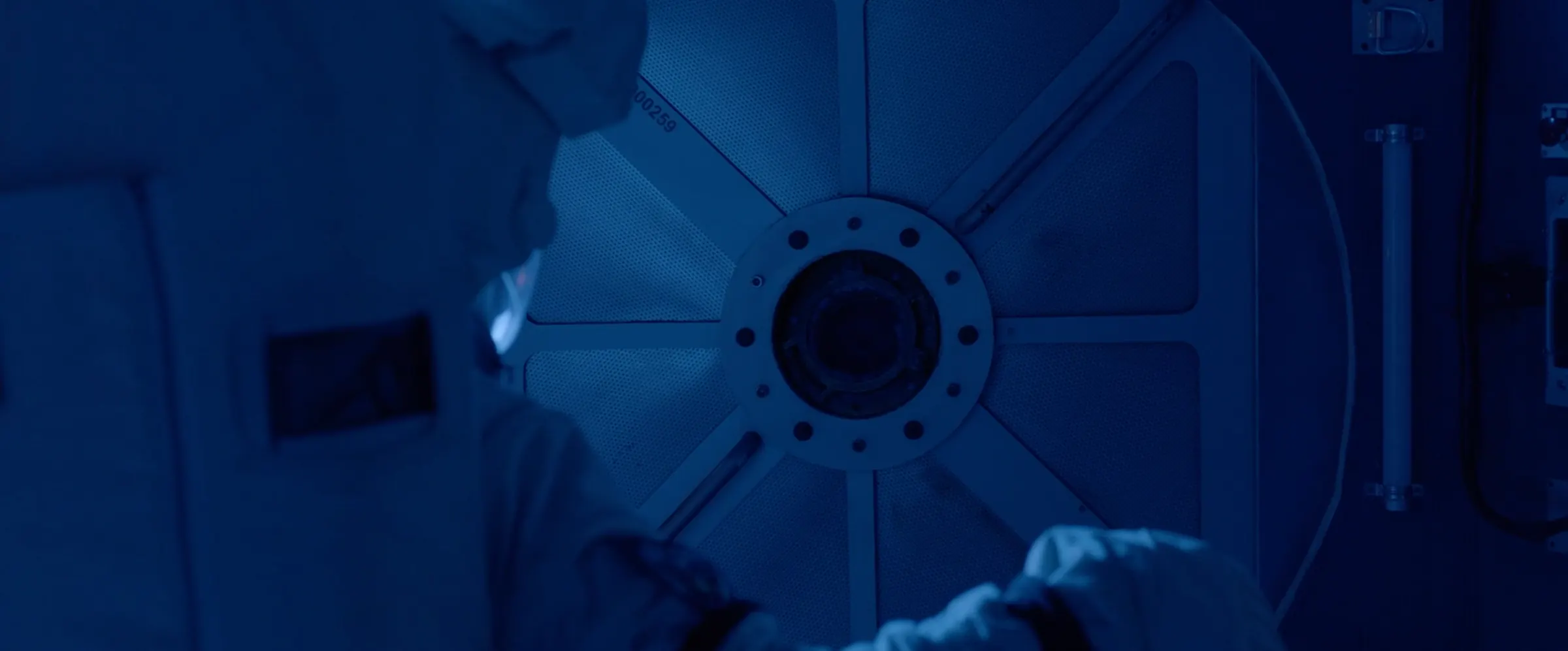 A circular airlock hatch in blue darkness.