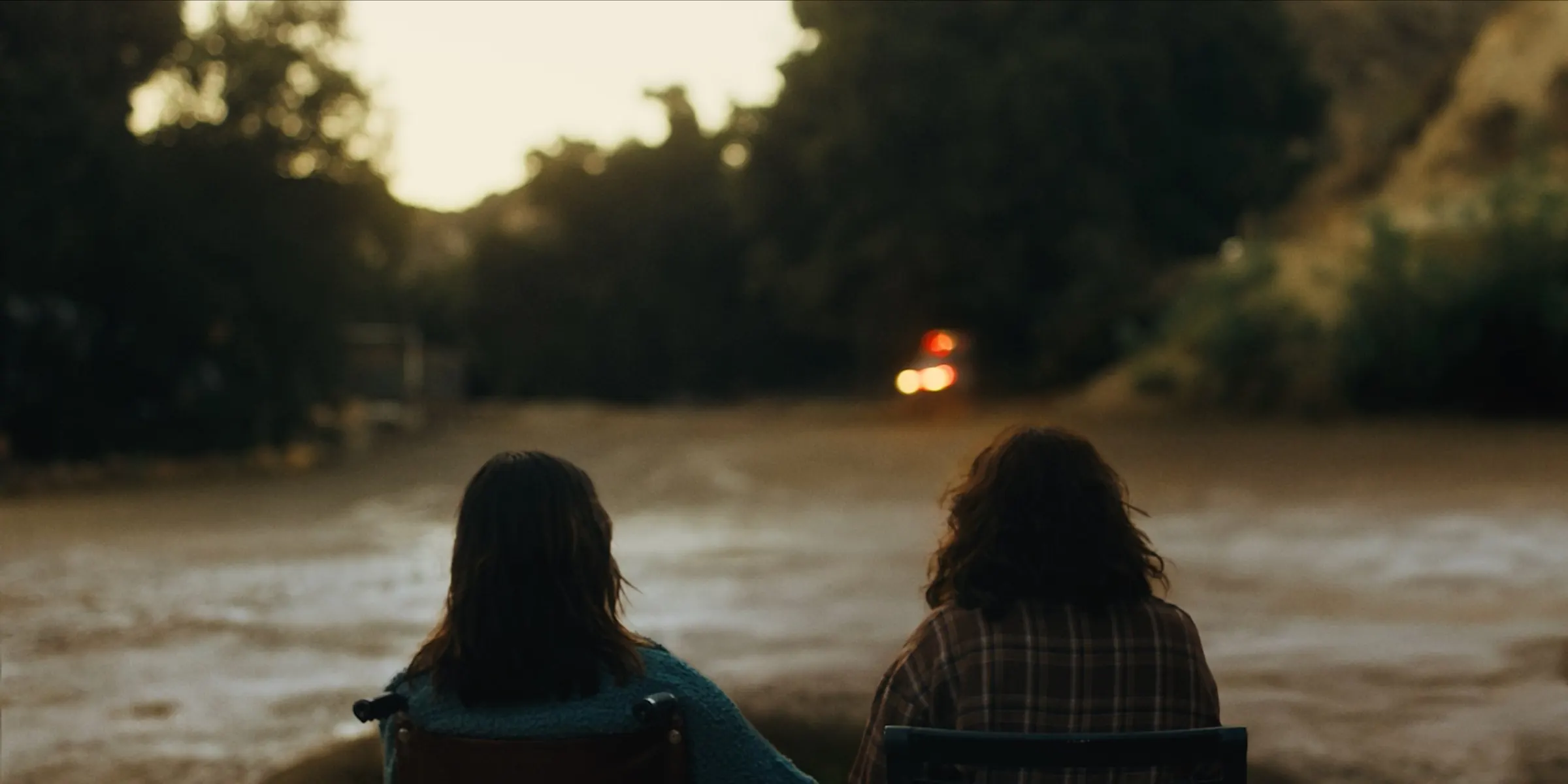 Two women look out over a flooded river at dusk.