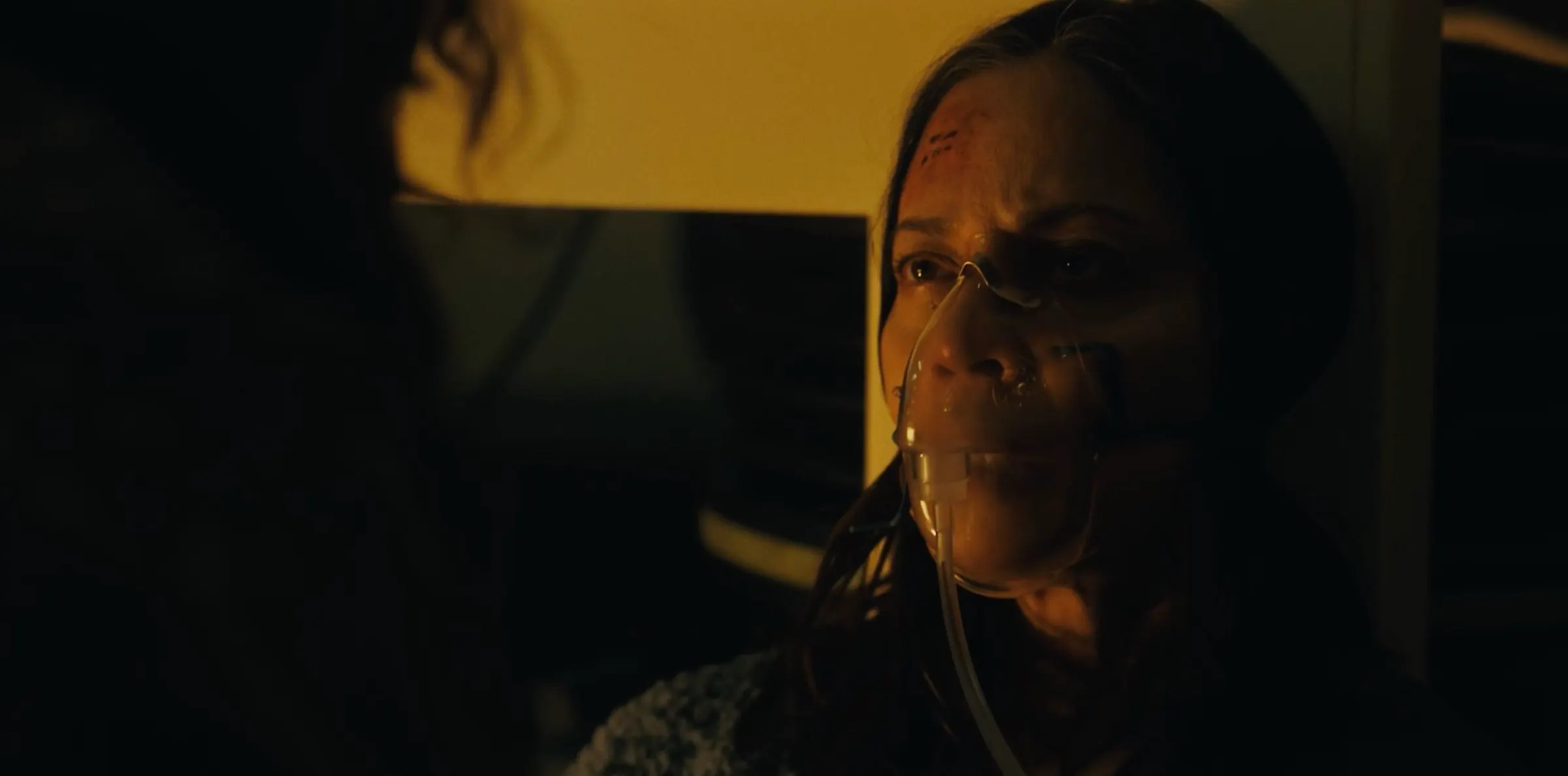 A woman’s face in low amber light.