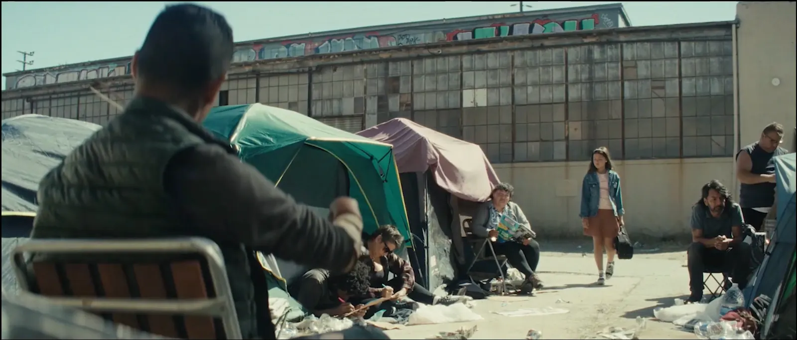 A man sits among tents on a Los Angeles street.