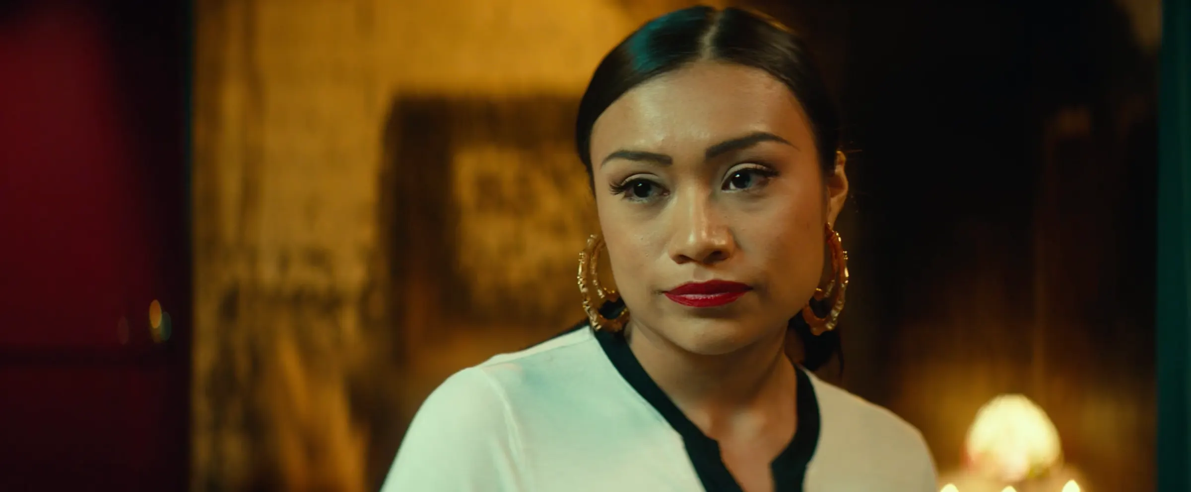 A sorority sister in gold hoop earrings, lit by lamplight.