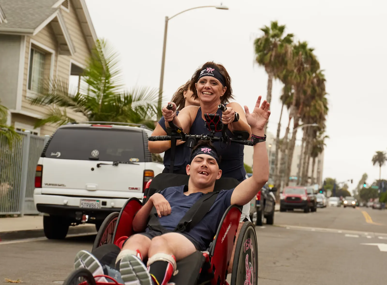 An Angel Rider and runner celebrate on a palm-lined street.