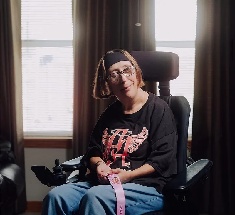 A woman sits in her wheelchair at home.