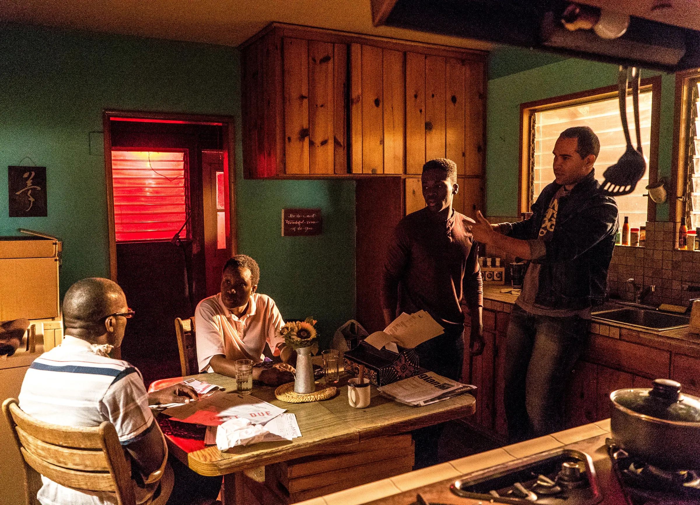 Cast and crew set up a family dinner scene in a wood-panelled kitchen.