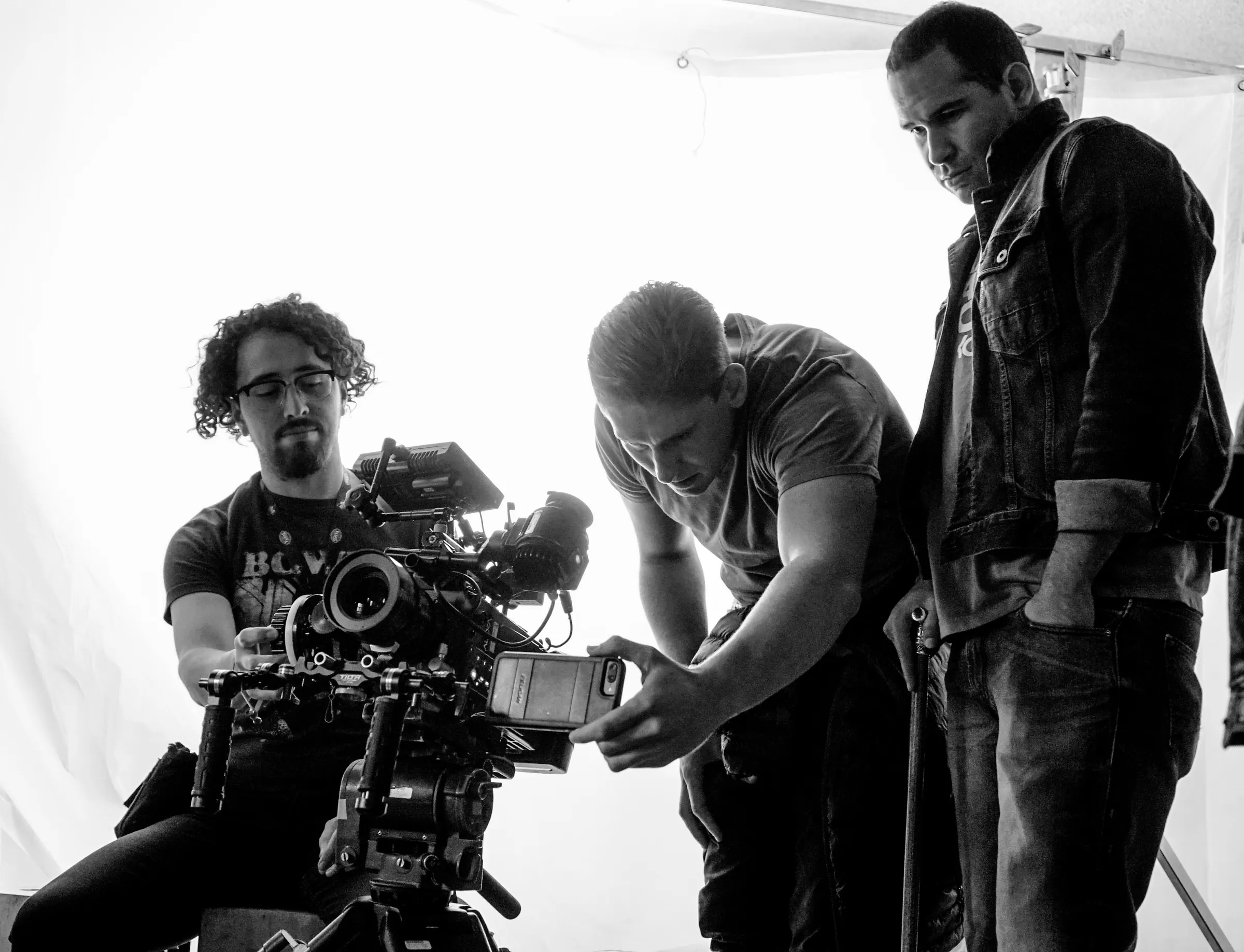 Black-and-white photo of the director and camera team checking a shot.