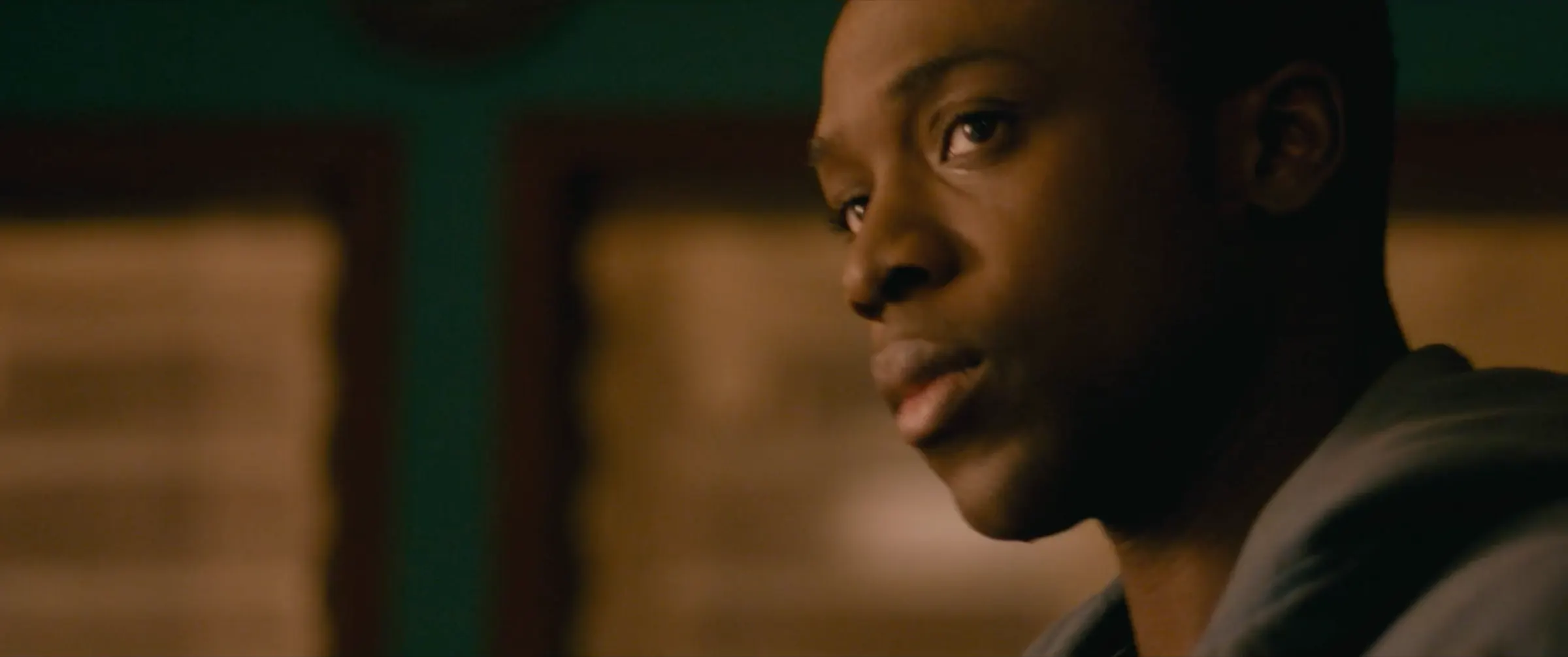 A young man looks over his shoulder in amber light.
